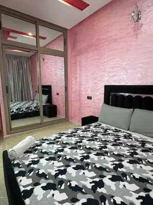 a bedroom with a black and white bed and a mirror at Appartement fes centre in Fès