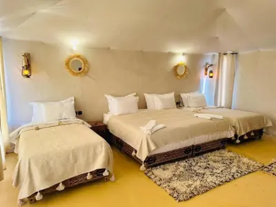 a bedroom with two beds and a mirror on the wall at White Camp Desert Safari in Merzouga