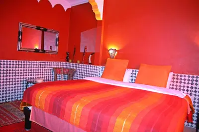 a red bedroom with a colorful bed in a room at Dar Ayour Todra Gorges in Aït Baha