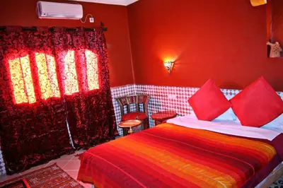 a bedroom with a bed with red walls and red curtains at Dar Ayour Todra Gorges in Aït Baha