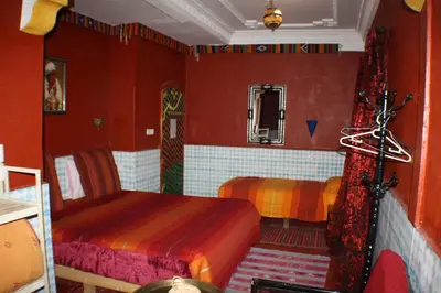 a bedroom with two beds and red walls at Dar Ayour Todra Gorges in Aït Baha