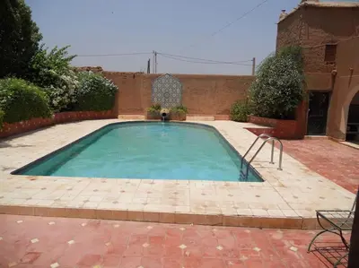 a large swimming pool in a courtyard with a brick building at John's Place in Marrakech