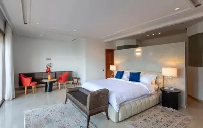 a bedroom with a large bed and a table and chairs at Villa Lamaan - Domaine prive piscine et hammam in Douar bel Rhanodour