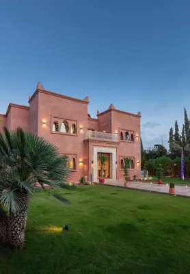 a large house with a palm tree in front of it at Villa Lamaan - Domaine prive piscine et hammam in Douar bel Rhanodour