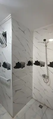 a bathroom with a shower with white marble walls at Superbe appartement à Meknes in Meknès