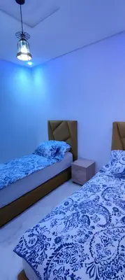 two beds in a room with a blue light at Superbe appartement à Meknes in Meknès