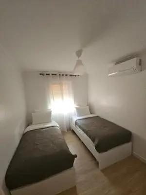 a bedroom with two beds and a window with the sunlight at Appartement équipé! in Ouarzazate
