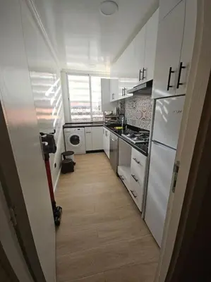 a small kitchen with white appliances and a hallway at Appartement équipé! in Ouarzazate