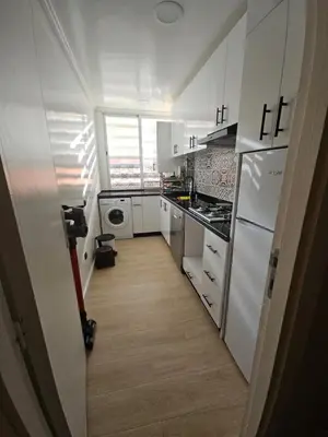 a small kitchen with white appliances and a hallway at Appartement équipé! in Ouarzazate