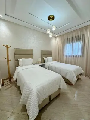 a bedroom with two beds and a cross on the wall at Appartement Moderne in Meknès