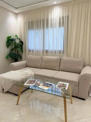 a living room with a couch and a glass table at Appartement Moderne in Meknès
