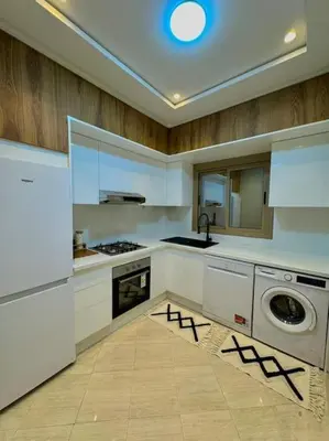 a kitchen with white cabinets and a washer and dryer at Appartement Moderne in Meknès