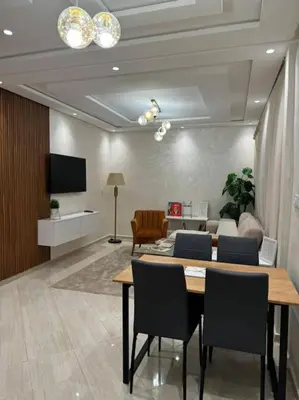 a room with a table and chairs and a living room at Appartement Moderne in Meknès