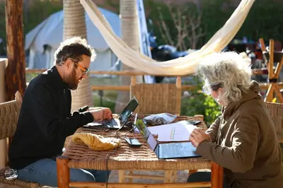 a man and woman sitting at a table with a laptop at Superides Camp in Ourika