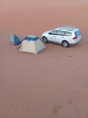 a car parked in the sand next to a tent at Time to Discover Wild Camp in Merzouga