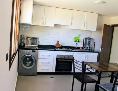 a kitchen with a washing machine and a table at شقق الاسد افران in Ifrane