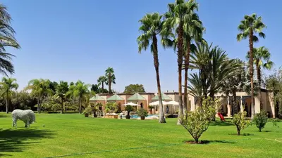 a horse grazing in a field in front of a house at Villa Alcázar Marrakech in Had Abdallah Rhiat