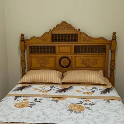 a bed with a wooden headboard and pillows at residence kawtar in Meknès