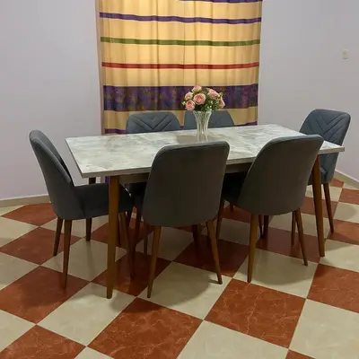 a table with chairs and a vase of flowers on it at residence kawtar in Meknès