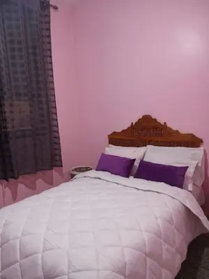 a bedroom with a large white bed with purple pillows at residence kawtar in Meknès