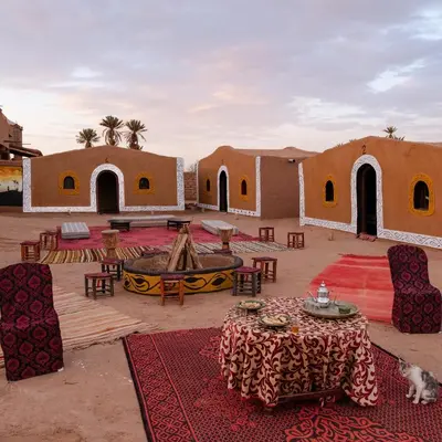 a desert encampment with tables and chairs and buildings at Nomads Heaven Camp in Mhamid