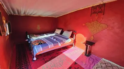 a bedroom with a bed in a red room at Nomads Heaven Camp in Mhamid