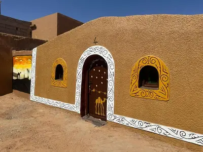 a building with a door and windows in the desert at Nomads Heaven Camp in Mhamid