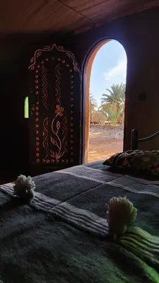 a bed in a room with an open window at Nomads Heaven Camp in Mhamid