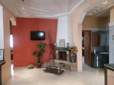 a living room with a fireplace and a tv on a wall at séjour confort et design à Fès in Fès