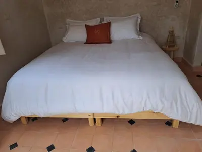 a large bed with white sheets and a red pillow at Villa Rahma in Marrakech