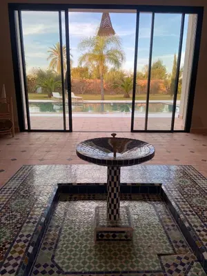 a fountain in a room with a view of a pool at Villa Rahma in Marrakech