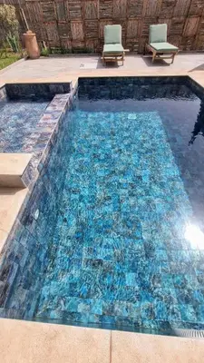 a swimming pool with blue water and two chairs in it at Stylish hôtel in Marrakech
