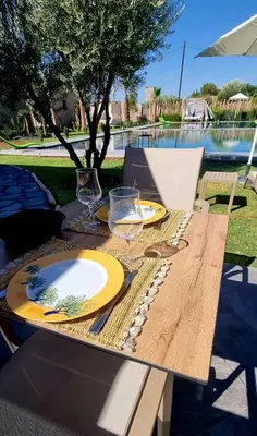 a wooden table with yellow plates and glasses on it at Stylish hôtel in Marrakech