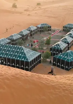 a group of green buildings in the desert at Sahara mirage camp in Merzouga