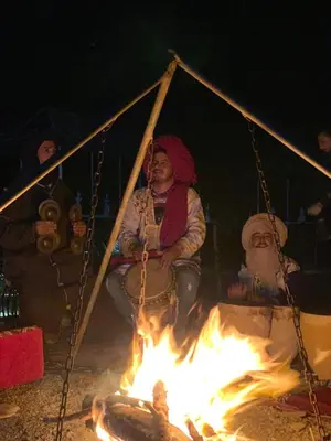a group of people sitting around a fire at Sahara mirage camp in Merzouga