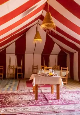 a dining room with a table and a red and white tent at Sahara mirage camp in Merzouga