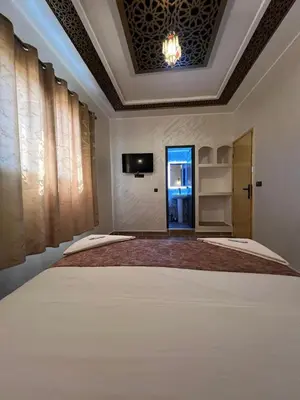 a bedroom with a large bed and a tv on the ceiling at Merzouga Dunes Apartment in Merzouga