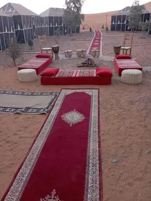 a group of red carpets sitting in the desert at Mars Desert Camp Merzouga in Merzouga