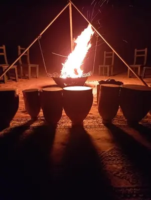 a fire inront of a group of bowls with flames at Mars Desert Camp Merzouga in Merzouga