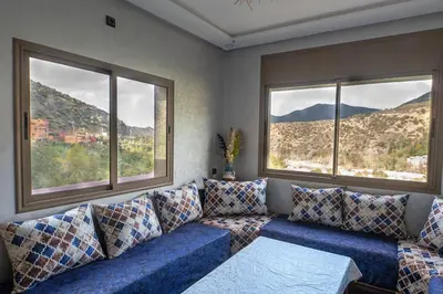a living room with a blue couch and two windows at Bab Atlas appartment N3 in Ourika valley in Aghbalou