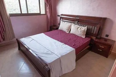 a bedroom with a bed with a wooden headboard at Bab Atlas appartment N5 in Ourika valley in Aghbalou