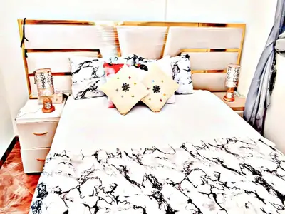 a bed with a black and white comforter and pillows at Luxury 3-bedroom apartments 5-min to the Airport in Fès
