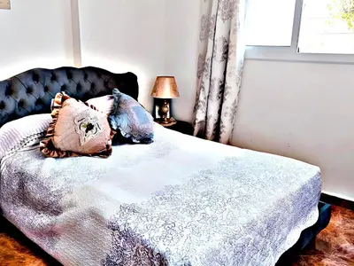 a bedroom with a bed with a black headboard and pillows at Luxury 3-bedroom apartments 5-min to the Airport in Fès