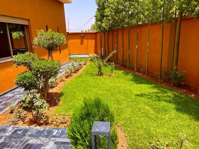 a garden with grass and trees next to a building at Villa avec piscine et jardin in Marrakech