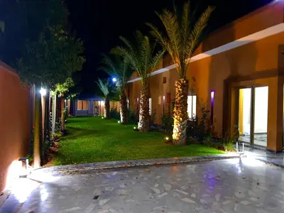 a courtyard with palm trees and a building at night at Villa avec piscine et jardin in Marrakech