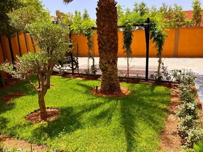 two trees in a yard with grass and a fence at Villa avec piscine et jardin in Marrakech
