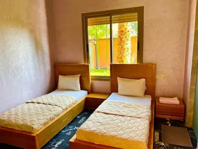 two beds in a room with a window at Villa avec piscine et jardin in Marrakech