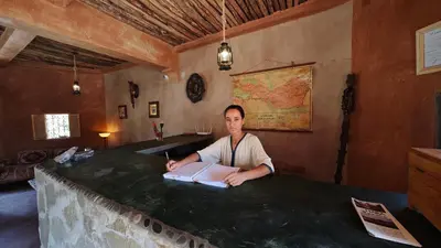 a woman sitting at a table with a book at Lodge Hara Oasis in Agdz