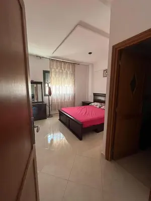 a bedroom with a bed with a red bedspread at très joli appartement a coté de l'airport fes in Oulad Tayeb