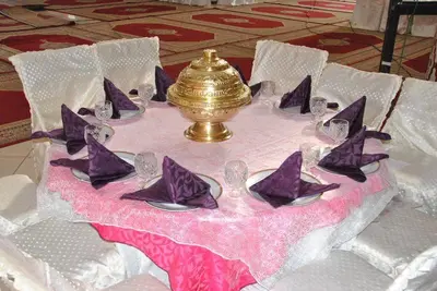 a table with purple napkins and a gold urn on it at Hotel OUM EL FADL in Fkih Ben Salah